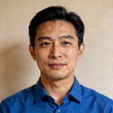 C7官方平台发行负责人人物头像照片，蓝色衬衫，背景为纯色墙面