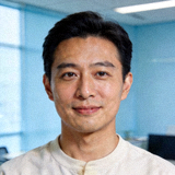 C7官方平台美术总监人物头像照片，浅色上衣，背景为浅蓝色办公环境